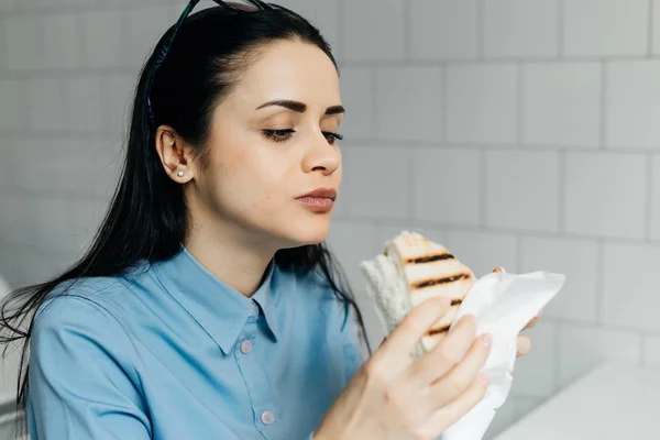 Dość młoda dziewczyna student w niebieska koszula sandwich śniadanie w kawiarni po Klasa — Zdjęcie stockowe