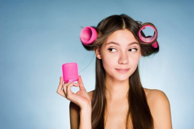 düşünceli bir genç kız güzel bir saç modeli, başına büyük bir pembe kıvırıcı istiyor.