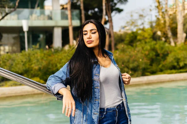 Attractive long-haired brunette posing in the sun in the city of Baku, against the background of water — Stock Photo, Image