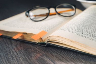 ahşap yüzeyde yer imleri, siyah jant gözlük ile bir kitaptır