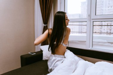 uzun saçlı bir kız erken uyanır, yatağında oturur ve kalkmak istemiyor