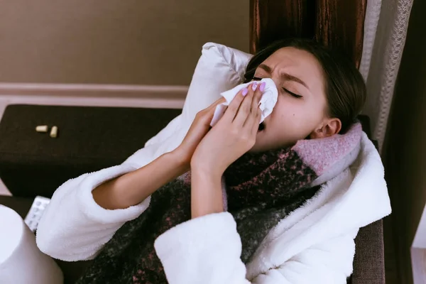 O fată tânără s-a îmbolnăvit, o eșarfă caldă în jurul gâtului, o durere în gât, strănută — Fotografie, imagine de stoc
