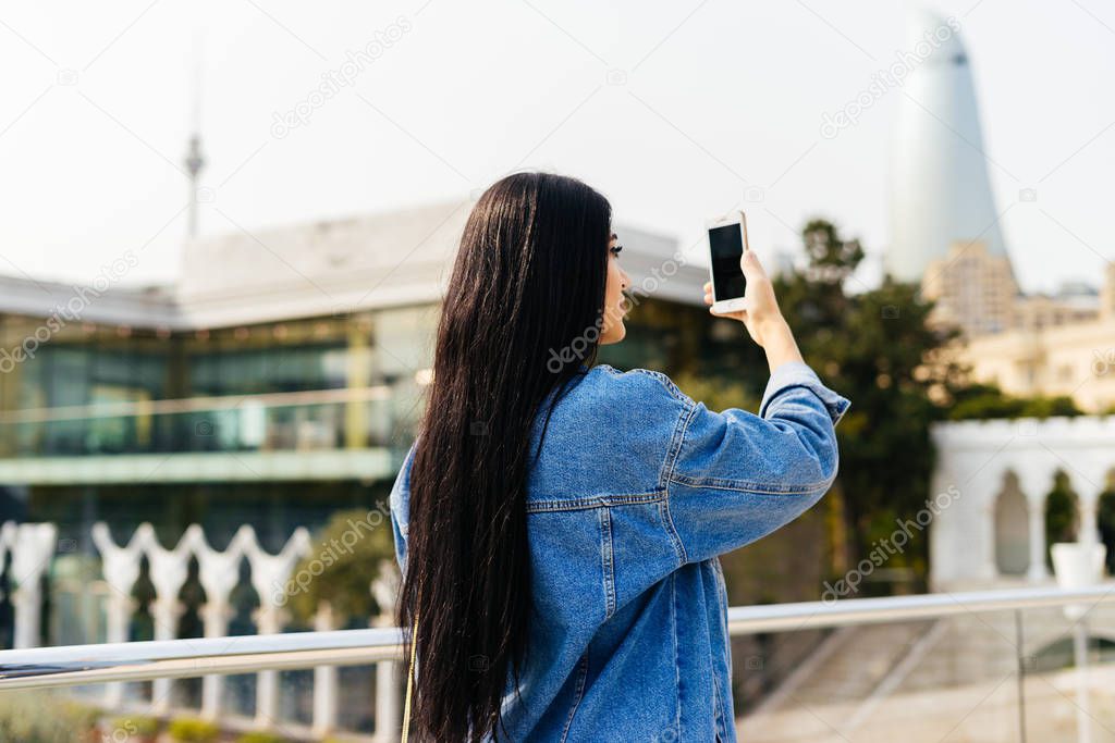 stylish long-haired girl travels, takes pictures of the city of Baku