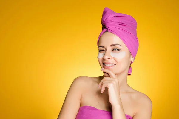 Junges Mädchen mit rosa Handtuch auf dem Kopf zwinkert und lächelt unter den Augen weißer Silikonflecken — Stockfoto