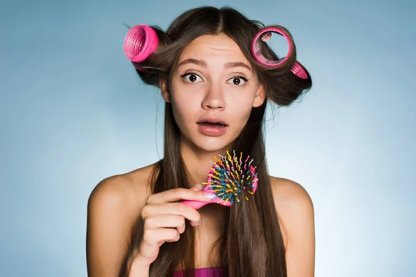 Удивлённая девушка делает стильную прическу с бигудями и расчёсками — стоковое фото