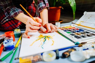 Kız ressam bir beyaz kağıt bir fırça ve suluboya ile üzerinde çizer