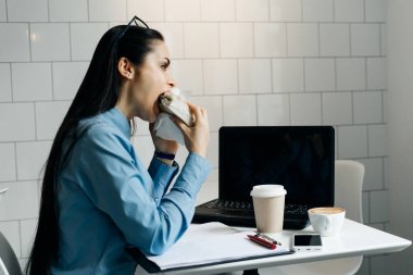 mutlu genç esmer kız serbest meslek sahibi bir sandviç ve kahve ile bir kafede Kahvaltı