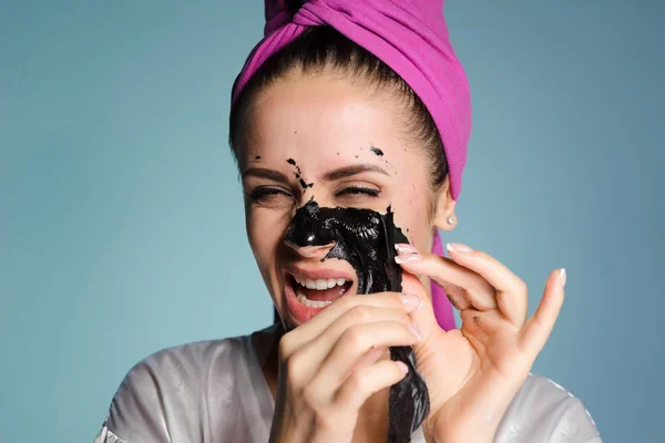 面白い少女は彼女の顔から黒クレンジング マスクを削除し、彼女の不愉快です。 — ストック写真