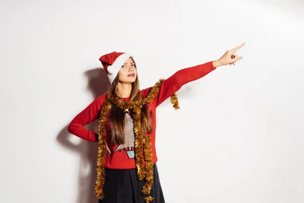 Divertente ragazza in abiti rossi, con un fili di lame d'oro sul collo punta a qualcosa con il dito, il nuovo anno 2018 — Foto Stock
