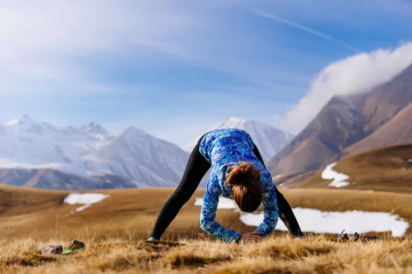 Aktivní mladá dívka v modrém saku vede zdravého životního stylu, zabývající se jóga na pozadí pohoří Kavkaz — Stock fotografie