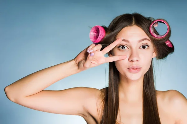 La fille montre deux doigts sur la tête des bigoudis pour créer une belle coiffure — Photo