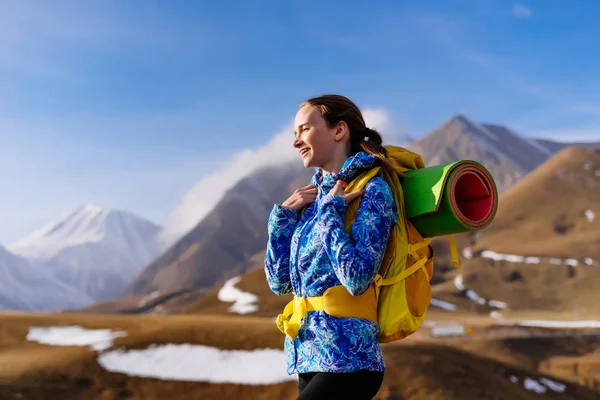 Feliz joven con una chaqueta azul viaja a lo largo de la cresta del Cáucaso, disfruta del sol y la calidez —  Fotos de Stock