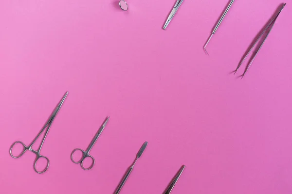 На рожевій поверхні медичні стоматологічні інструменти — стокове фото