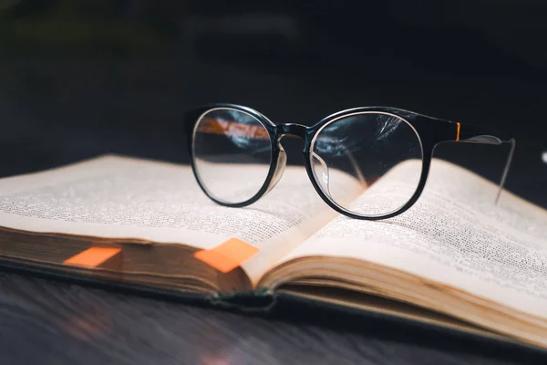 Livro velho com óculos emoldurados preto sobre ele, close-up, notas no livro — Fotografia de Stock