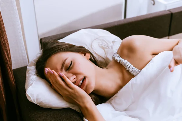 Assonnato scontento giovane ragazza si trova a letto, la sveglia squillato, non vuole alzarsi — Foto Stock