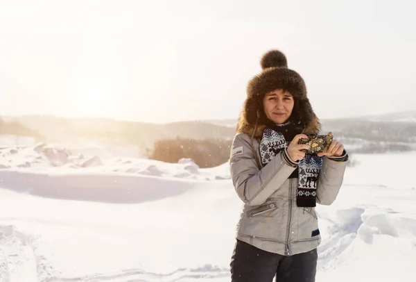 Młoda dziewczyna podróżuje przez zimno Islandii, w kapeluszu ciepłego futra, posiada aparat fotograficzny — Zdjęcie stockowe