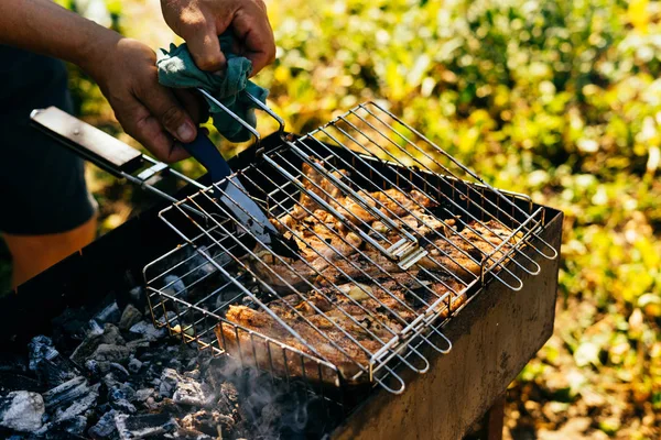 Человек-охотник готовит сырое мясо оленя на гриле на пикнике — стоковое фото