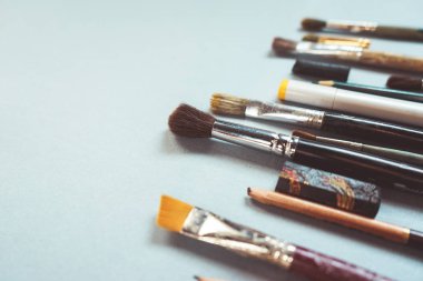 Mavi yüzeyde Sanat fırçalar farklı boyutlarda, kurşun kalem ve tükenmez kalem vardır