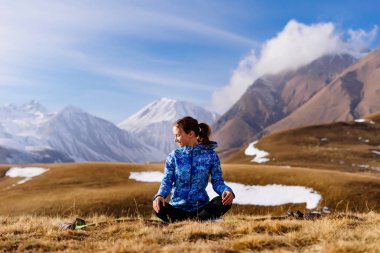 etkin kız yoga yapar ve sağlıklı bir yaşam tarzı olur, doğa ve Kafkas Dağları sahiptir, yere oturur