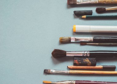 mavi bir tabloda farklı boyutlarda, kalemler ve işaretleyiciler sanatsal fırçaların çoğu