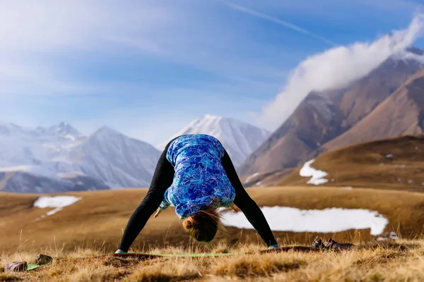 active girl is engaged in yoga and leads a healthy lifestyle, in nature, in the background of the Caucasus Mountains