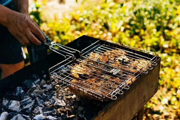 Homem caçador fritar carne de veado crua em uma grelha para um piquenique na natureza — Fotografia de Stock