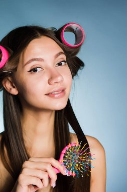 genç çekici kız bir kıvırıcı ile güzel bir saç modeli yapar, bir tarak onun elinde tutar