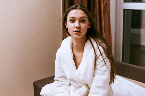Όμορφη ελκυστική κοπέλα κάθεται σε ένα κρεβάτι σε ένα λευκό terry πετσέτα — Φωτογραφία Αρχείου