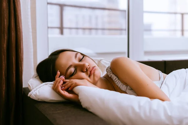 Joven durmiendo en la cama junto a la ventana, no quiere levantarse —  Fotos de Stock