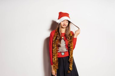 Kırmızı şenlikli elbiseleri, genç güzel kız görünüyor üzgün, saçlarını dokunur, yeni yıl için bekler