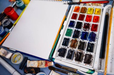 sanat malzemeleri, suluboya ve beyaz kağıt, guaş masaya vardır