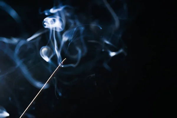 På svart bakgrund pyrande aromatiska stick, blå rök — Stockfoto