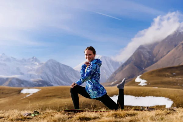 Счастливая спортивная девушка занимается йогой в горах Кавказа, наслаждаясь теплой погодой и чистым воздухом — стоковое фото