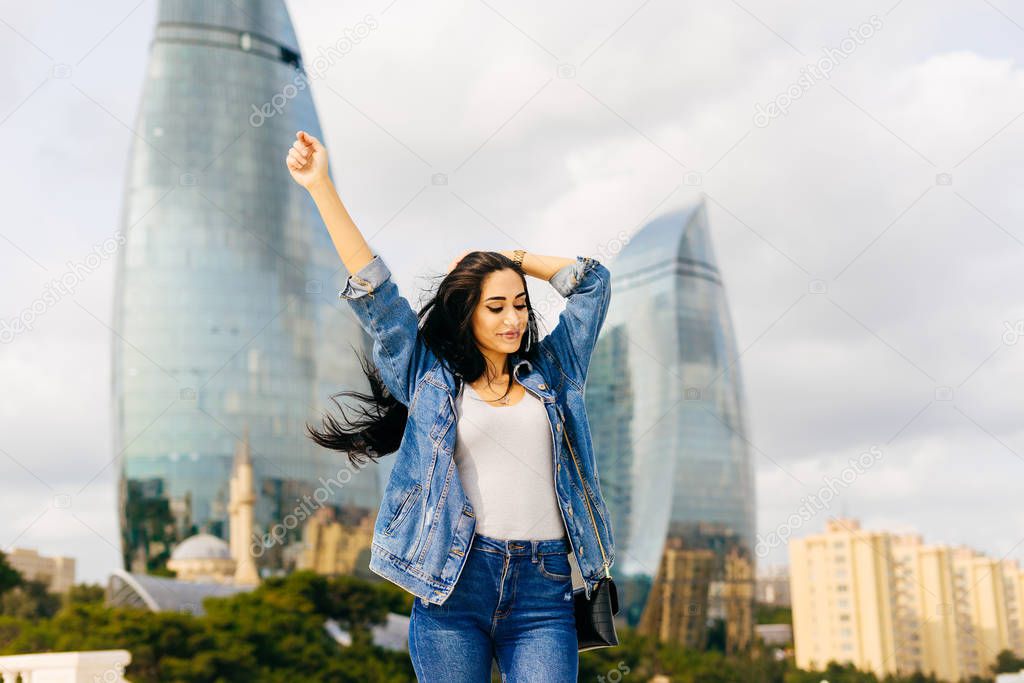 happy black-haired girl travels through Europe, raised her hands up, she likes Baku