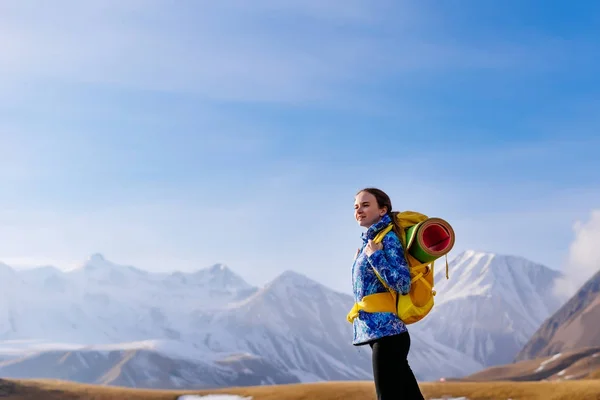 Una joven activa con una chaqueta azul viaja a través de las montañas del Cáucaso con una mochila y una tienda de campaña, disfrutando de aire limpio —  Fotos de Stock