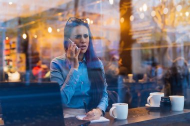 memnun meşgul kız freelancer telefonla, bir kafede müzakere