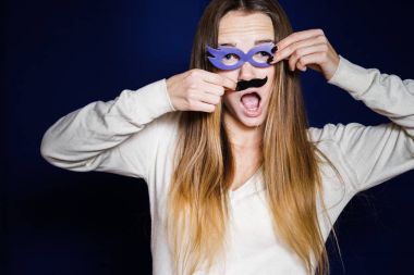 Beyaz bir ceketi giyen garip bir sarışın genç kız onun elleri genel gider gözlükler ve bıyıklı tutan bir maskeli balo için gidiyor