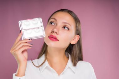 genç güzel kız Beyaz gömlekli sahte kirpik, kaydırılan paketiyle düşünceli yukarı seyir tutuyor