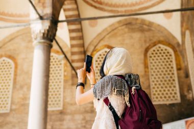 Bir eşarp genç bir kadında telefonda Camii avlusunda fotoğraf çeker