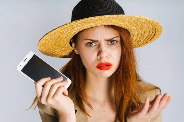 Triste jovem ruiva menina em um chapéu de palha detém um smartphone — Fotografia de Stock