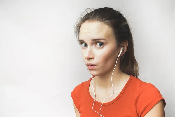 Mulher surpreso em fones de ouvido, em uma camiseta vermelha — Fotografia de Stock