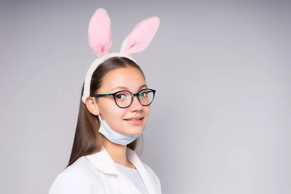 Una bella ragazza sorridente con gli occhiali, una vestaglia medica bianca, un bordo dell'orecchio lunetta sulla testa — Foto Stock