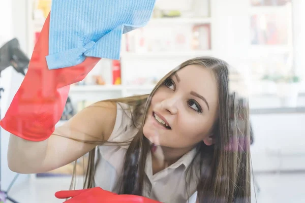 Young smiling girl in red gloves washing a window with a rag — Stock Photo, Image