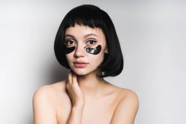 çekici genç kız siyah saçlı cheny silikon yamalar gözleri altında kamera bakar