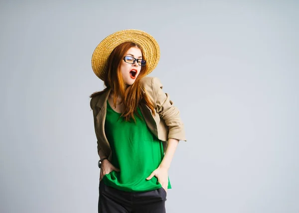 Divertente sorpreso ragazza dai capelli rossi in un cappello di paglia, giacca verde e occhiali pose — Foto Stock