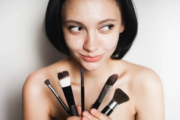 Çekici genç kız siyah saçlı eller kozmetik makyaj fırça tutar — Stok fotoğraf