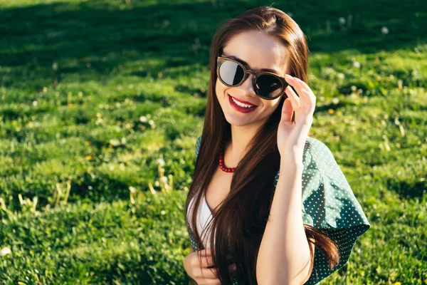 Bella donna su sfondo erba, occhiali da sole, sorriso — Foto Stock
