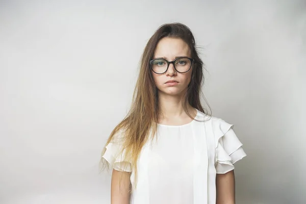 Aufgebrachtes junges Mädchen mit Brille und weißem T-Shirt, das in die Kamera blickt — Stockfoto