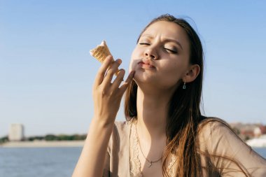 memnun genç kız dondurma yiyor, yüzüne güneş parlıyor