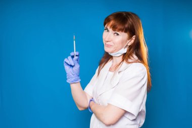 Beyaz tıp sabahlık deneyimli Kızıl saçlı kadın doktor gülümseyen bir şırınga elinde tutan